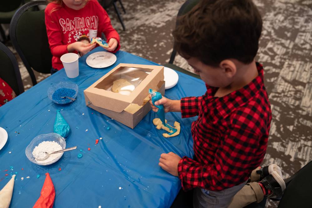 A boy decorating an anchor cookie.